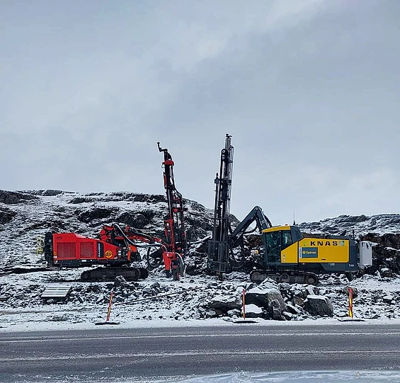 Gravemaskin på steinhaug