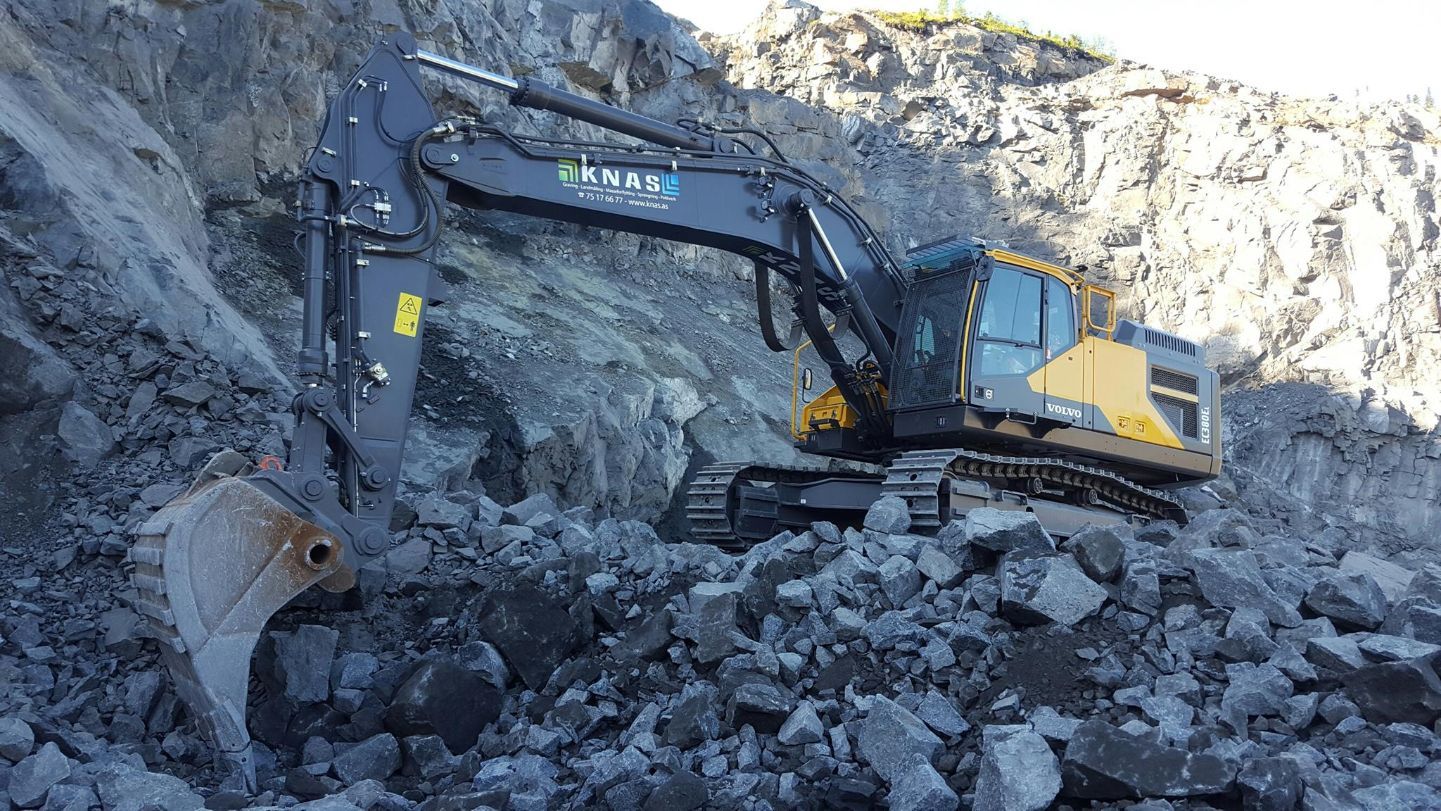 Gravemaskin på steinhaug