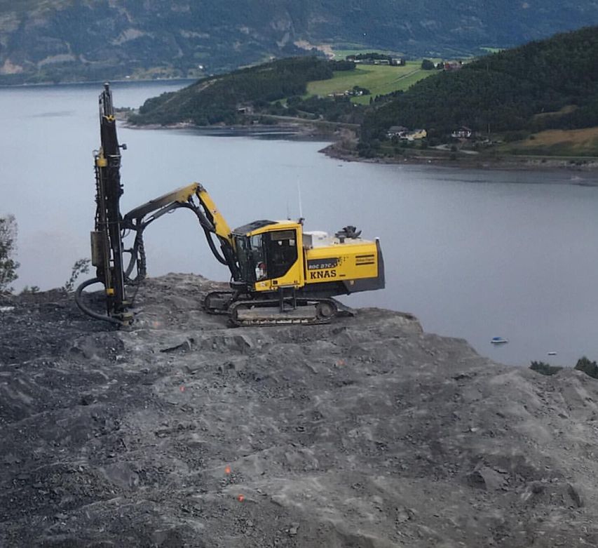 Gul gravemaskin ved sjøen