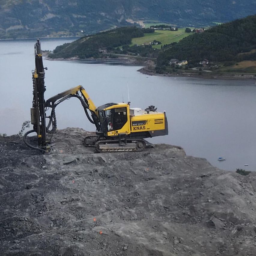 Gul gravemaskin ved sjøen