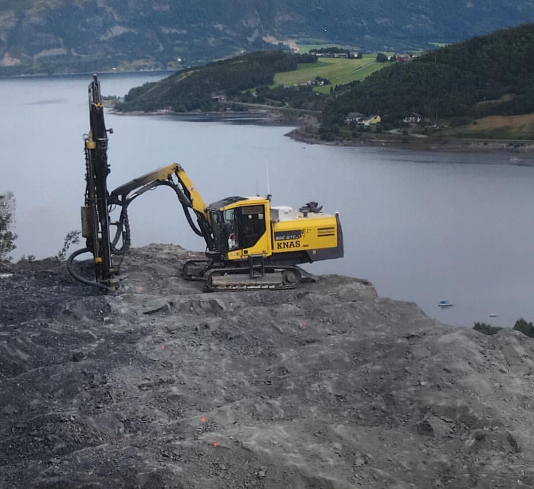 Gul gravemaskin ved sjøen